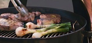 Carne asada y cebollitas asándose en la parrilla de carbón